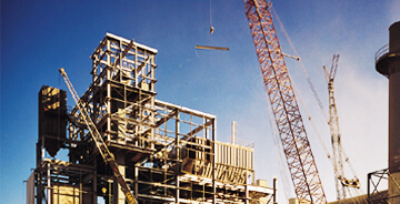 Two cranes moving construction material at an industrial construction job-site