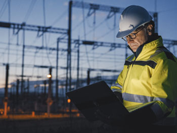 Electrician working on a lap with electrical powerlines in background