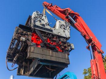 Crane lifting a large machine for a custom industrial rigging project